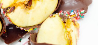 Çikolata kaplı bir elma, üzerine de şeker serpiştirilmiş. Renkli tatlılar