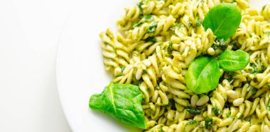 Üstünde ıspanak olan bir tabak makarna. Ispanak taze ve yeşildir ve makarna pişirilir ve yenmeye hazırdır. Yemek sağlıklı ve lezzetli görünüyor.