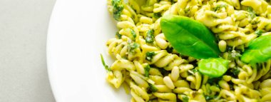 Üstünde ıspanak olan bir tabak makarna. Ispanak taze ve yeşildir ve makarna pişirilir ve yenmeye hazırdır. Yemek sağlıklı ve lezzetli görünüyor.