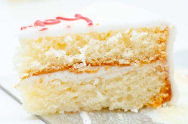 Üstünde renkli krema olan bir dilim beyaz pasta. Pasta ikiye bölünmüş ve üzerinde krema tasarımı var.