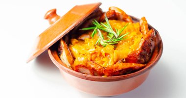 Bir kase yiyecek, et ve lahana turşusu. Yemek portakallı ve lezzetli bir tadı var. Tencere kahverengi ve kırsal, topraksı bir hissi var.