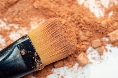 Makyaj fırçası toz yığınının üzerinde duruyor. Fırça siyah ve sarı ve toz kahverengi. Yaratıcılık ve kendini ifade etme kavramı, makyajın kişinin görünüşünü iyileştirmek için sık sık kullanıldığı gibi.