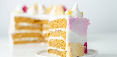 Üstünde pembe, sarı ve beyaz krema olan bir dilim pasta. Pasta katmanlar halinde kesilmiş ve üzerinde pembe beyaz krema var.