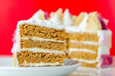 Üstünde pembe, sarı ve beyaz krema olan bir dilim pasta. Pasta katmanlar halinde kesilmiş ve üzerinde pembe beyaz krema var.