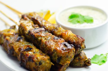 Bir tabak dolusu et, yanında sos ve ızgara yiyecek.