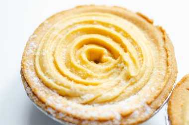 Tepesinde krema olan bir hamur işi. Şekerleme pudra şekerinden yapılmış ve spiral bir desen içinde yayılmış.