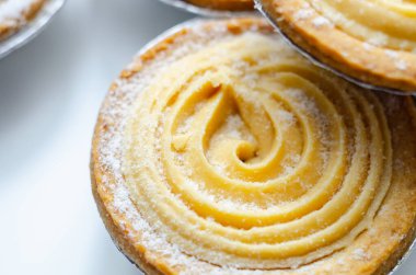 Tepesinde krema olan bir hamur işi. Şekerleme pudra şekerinden yapılmış ve spiral bir desen içinde yayılmış.