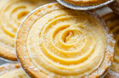 Tepesinde krema olan bir hamur işi. Şekerleme pudra şekerinden yapılmış ve spiral bir desen içinde yayılmış.