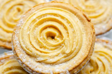 Tepesinde krema olan bir hamur işi. Şekerleme pudra şekerinden yapılmış ve spiral bir desen içinde yayılmış.