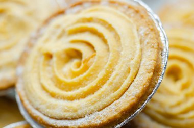 Tepesinde krema olan bir hamur işi. Şekerleme pudra şekerinden yapılmış ve spiral bir desen içinde yayılmış.