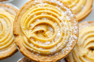 Tepesinde krema olan bir hamur işi. Şekerleme pudra şekerinden yapılmış ve spiral bir desen içinde yayılmış.