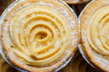 Tepesinde krema olan bir hamur işi. Şekerleme pudra şekerinden yapılmış ve spiral bir desen içinde yayılmış.