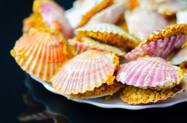 Üzerinde kabuk olan bir tabak yemek. Kabuklar pembe ve beyaz. Plakası siyah arka planda.