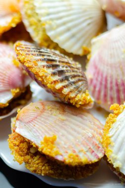 Üzerinde kabuk olan bir tabak yemek. Kabuklar pembe ve beyaz. Plakası siyah arka planda.