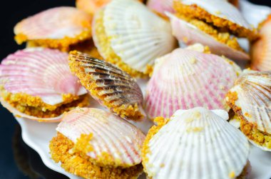 Üzerinde kabuk olan bir tabak yemek. Kabuklar pembe ve beyaz. Plakası siyah arka planda.