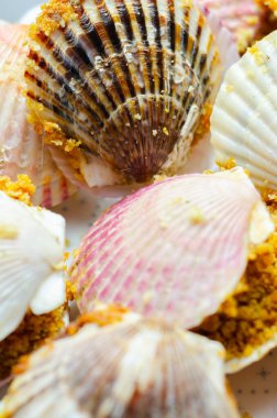 Üzerinde kabuk olan bir tabak yemek. Kabuklar pembe ve beyaz. Plakası siyah arka planda.