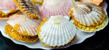 Üzerinde kabuk olan bir tabak yemek. Kabuklar pembe ve beyaz. Plakası siyah arka planda.