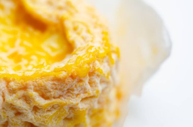 Sarı bir peynir kağıdın içinde duruyor, popüler yumuşak Fransız peynirleri.