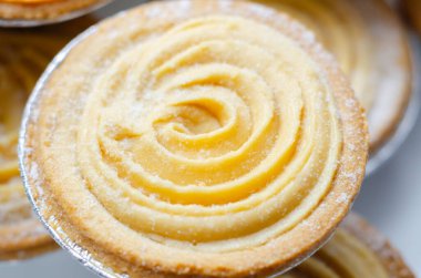 Tepesinde krema olan bir hamur işi. Şekerleme pudra şekerinden yapılmış ve spiral bir desen içinde yayılmış.