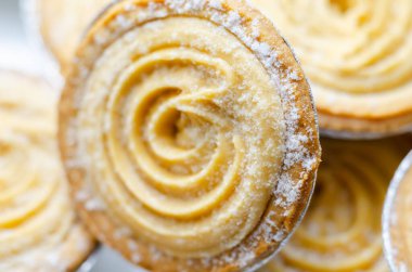 Tepesinde krema olan bir hamur işi. Şekerleme pudra şekerinden yapılmış ve spiral bir desen içinde yayılmış.