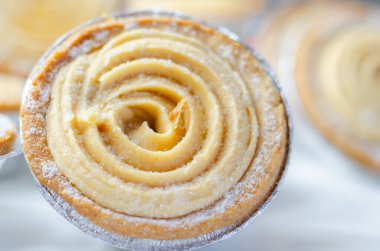 Tepesinde krema olan bir hamur işi. Şekerleme pudra şekerinden yapılmış ve spiral bir desen içinde yayılmış.