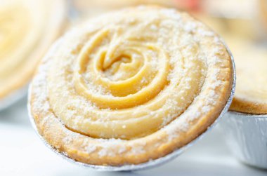 Tepesinde krema olan bir hamur işi. Şekerleme pudra şekerinden yapılmış ve spiral bir desen içinde yayılmış.