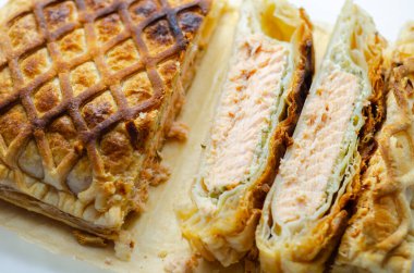 İçinde somon olan bir parça hamur işi kesilir. Hamur işi kahverengi ve çıtır çıtır bir dokusu var.