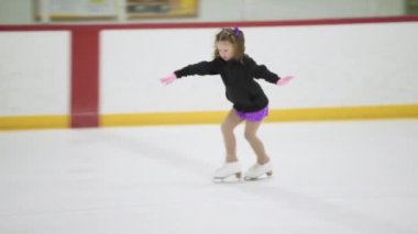 Küçük kız buz pateni pistinde artistik patinaj yapıyor..