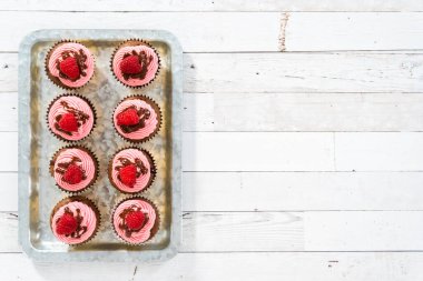 Düz yatıyordu. Çikolatalı ahududu kekleri çikolatalı ganache serpiştirilmiş ve üzeri ahududulu..