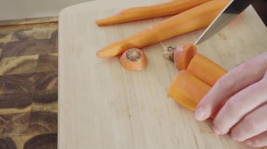 Ağaç kesme tahtasıyla büyük turuncu havuç kesiyor..