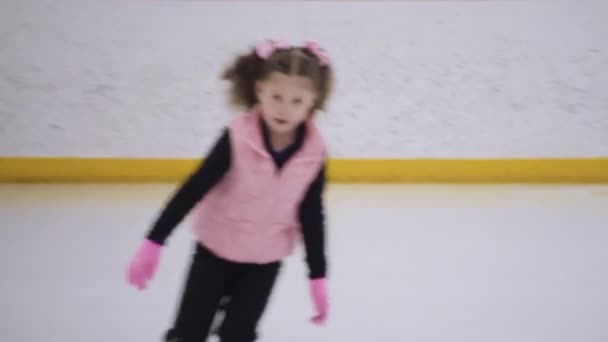 小さな女の子練習フィギュアスケートムーブオンザ屋内アイスリンク — ストック動画