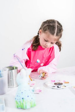 COVID-19 tecridi sırasında evde eğitim. Kağıt mache boyalı küçük kız Akrilik boyalı Paskalya tavşanı biblosu.