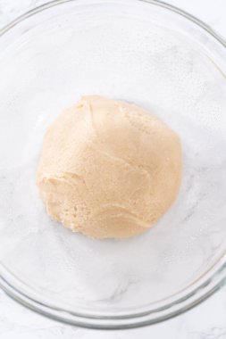 Tarçınlı tatlı pizzası hazırlamak için cam bir kasede pizza hamuru yetiştiriyorum..