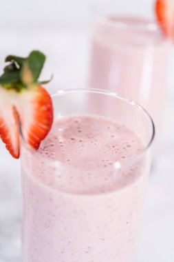 Taze taze çilek ve kağıt kamışla süslenmiş sağlıklı bir kahvaltı muzlu smoothie..