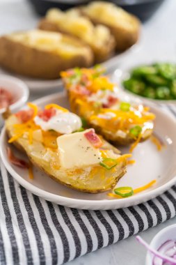 Fırında pişmiş patates. Tereyağı, ekşi krema, peynir ve pastırma parçalarıyla süslenmiş büyük fırında patates..