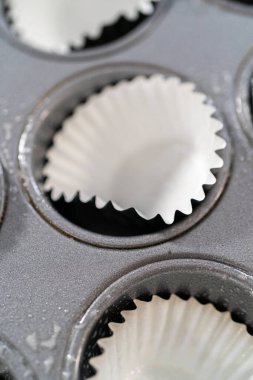 Scooping cupcake batter with dough scoop into a baking pan with liners to bake American flag mini cupcakes.