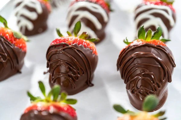 Organic strawberries dipped in chocolate drying on a parchment paper.