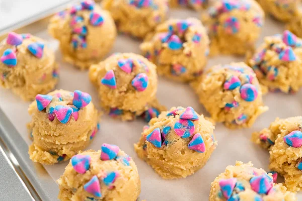 Chilled cookie dough scoops on the baking sheet to bake unicorn chocolate chip cookies.