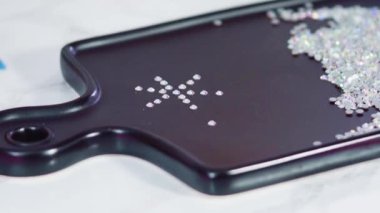 Beyaz yapay elmasların bolluğu siyah tahtada düz bir şekilde duruyor ve bir el işi projesine hazır..