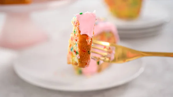 一歩ずつ 上にピンクのバタークリームのフリストと内側にバタークリームの充填でFunfettiバントケーキをスライス — ストック写真