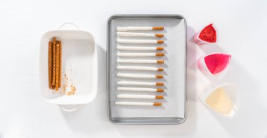 Düz yatıyordu. Çubuk krakerleri eritilmiş çikolatayla silikon bardağa batırıp Sevgililer Günü 'nde çikolata kaplı çubuk çubuk çubuklar yapmak..