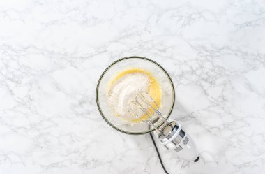 Düz yatıyordu. Mini vanilyalı kekler ve ombre pembe kremalı krema pişirmek için büyük bir karıştırma kabında malzemeler karıştırılıyor..