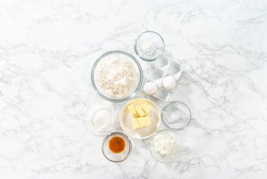 Düz yatıyordu. Bardaktaki ölçülü malzemeler mini vanilyalı kekler pişirmek için karıştırma kabı ve ombre pembe kremalı krema..