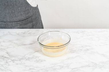 Küçük bir bardakta ıslak malzemeler karıştırmak mini vanilyalı kekler pişirmek için ombre pembe tereyağlı krema.