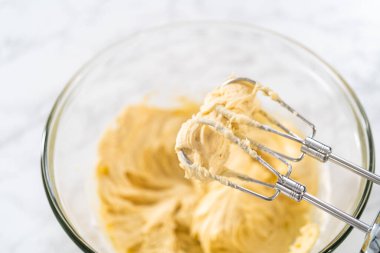 Mini vanilyalı kekler ve ombre pembe kremalı krema pişirmek için büyük bir karıştırma kabında malzemeler karıştırılıyor..