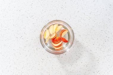 Düz yatıyordu. Kahverengileşmesinler diye su karışımında elma dilimleri yıkıyorum..