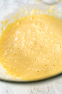 Mini vanilyalı kekler ve ombre pembe kremalı krema pişirmek için büyük bir karıştırma kabında malzemeler karıştırılıyor..