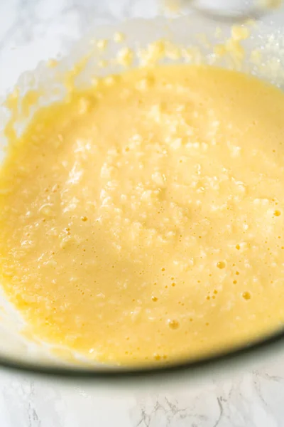 将配料和手搅拌器混合在一个大的搅拌碗里 用米黄色粉红奶油糖霜烤小香草杯蛋糕 — 图库照片