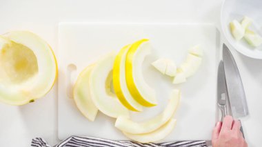 Adım adım. Düz yatıyordu. Beyaz kesme tahtasında kaygan altın çiğ taneli kavun.