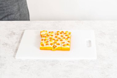 Beyaz bir kesme tahtasının üzerinde şekerli mısır şekerini kare parçalara ayırmak..